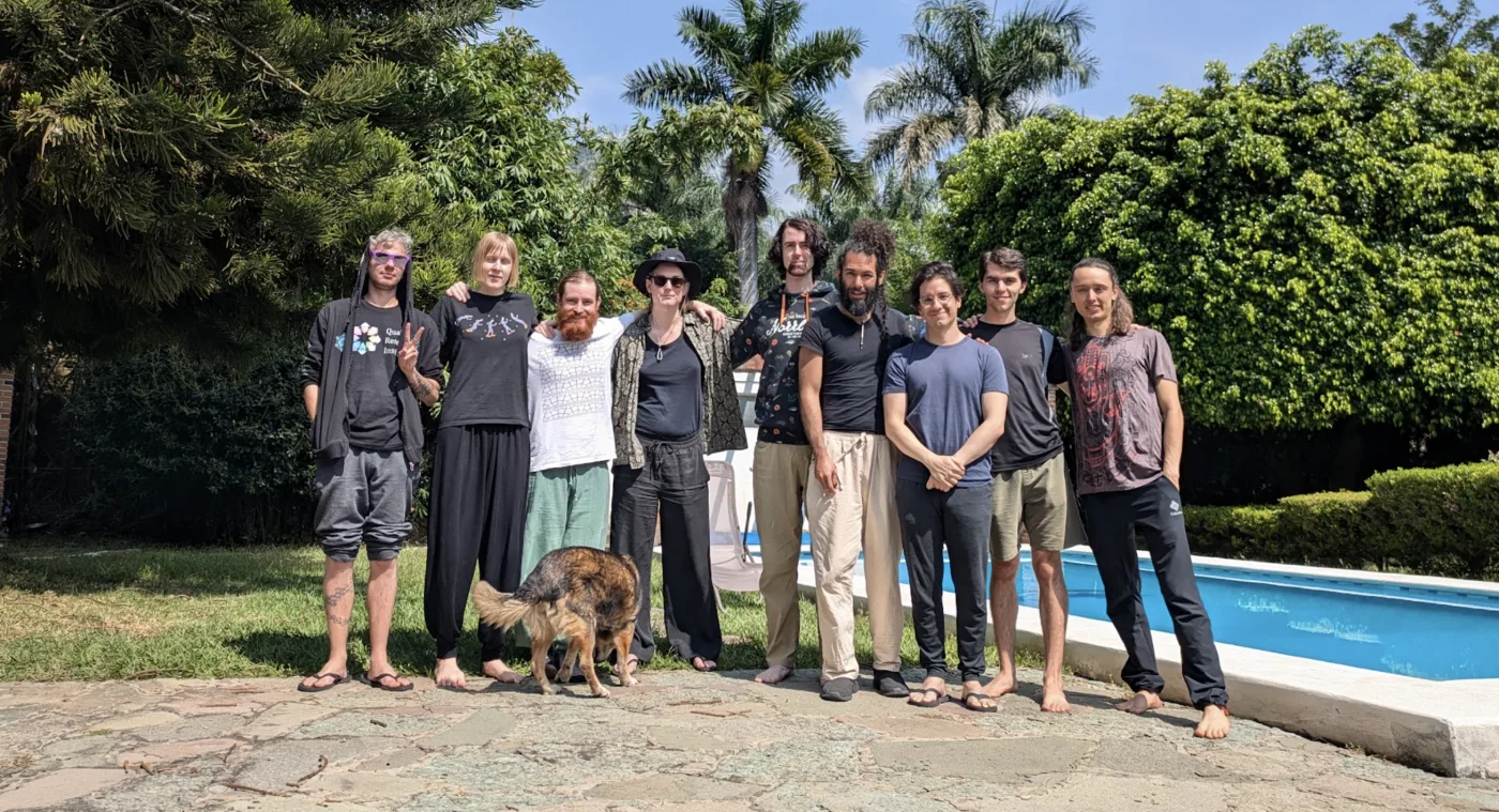 Group photo of researchers at the 2024 Tepoztlán workshop, standing by the pool with the mountain behind
